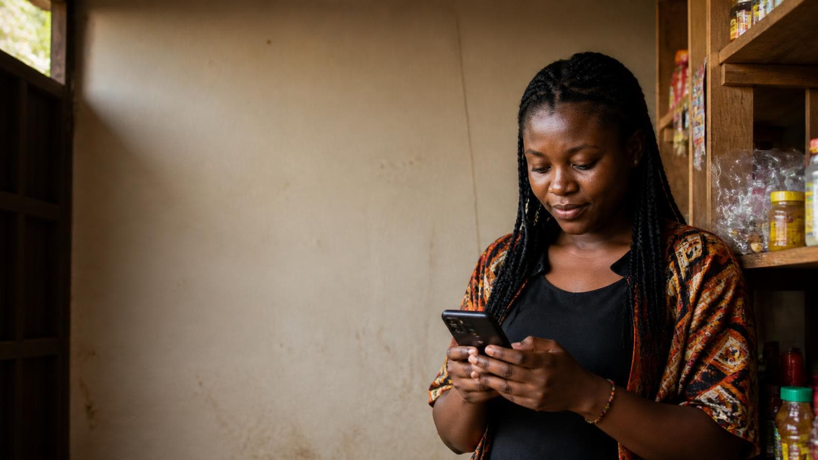 A trader in Buea checking the Sabbi app on her phone inside her shop